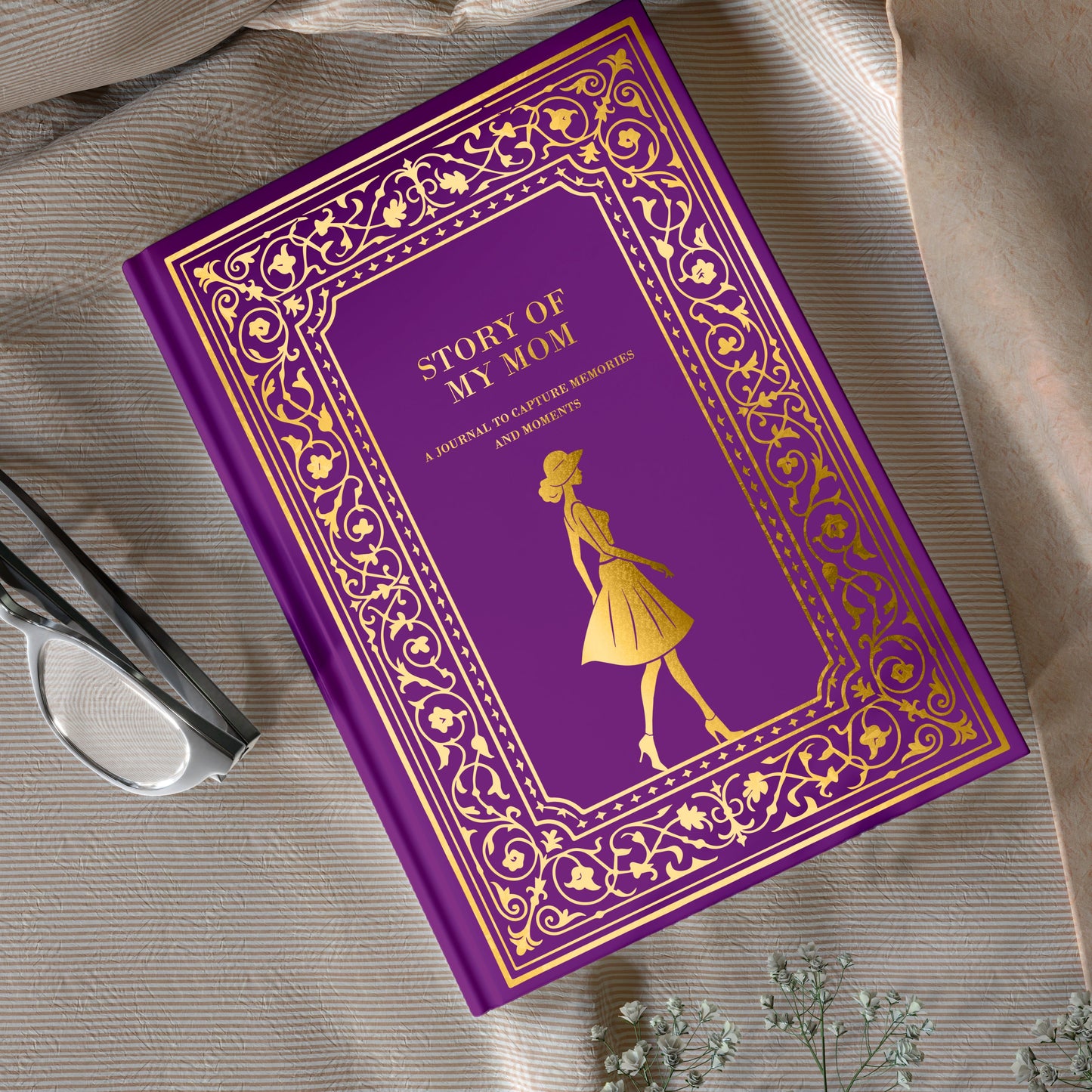 Purple book titled 'Story of My Mom' on a textured surface with flowers.